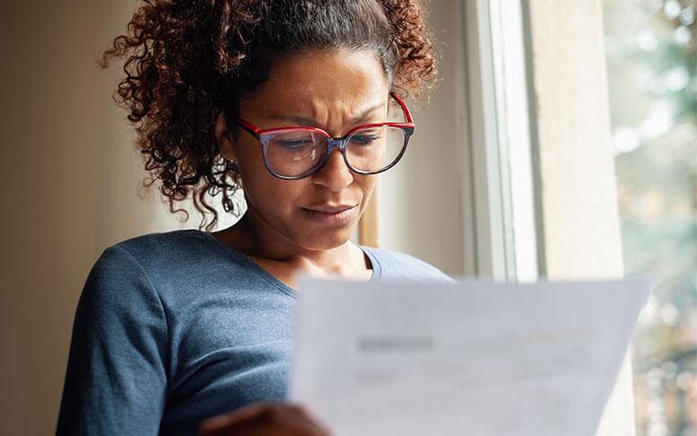 Portrait of worried woman standing beside window looking at her letter