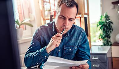 Man carefully revising a resume at his desk