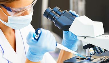 Beautiful woman in a laboratory working with a microscope.