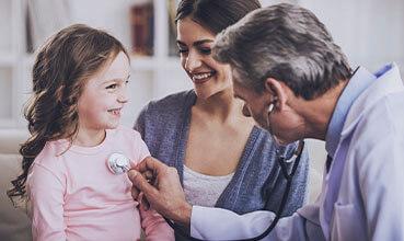 Pediatrician checks breath stethoscope a little girl in the arms of mother.