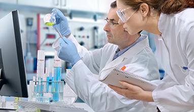 Woman toxicologist taking notes from male toxicologist in a science lab