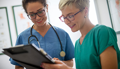 Female doctor and nurse with stethoscope looking at the clipboard 