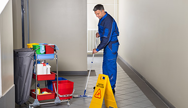Full length of mature male worker with broom cleaning corridor