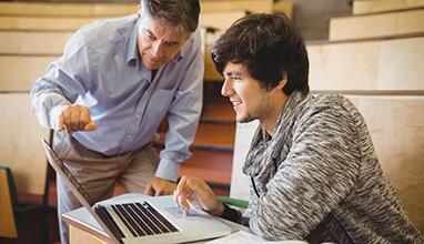 Professor helping a student in classroom at college