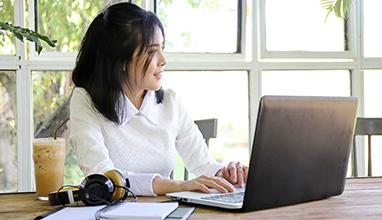 Woman writing on her laptop in for her advice column on her desk