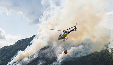 Helicopter flying above burning mountain