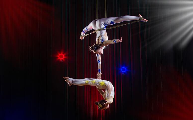 Two girls perform acrobatic elements in the air.