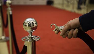 Usher opening a rope barrier to a red carpet