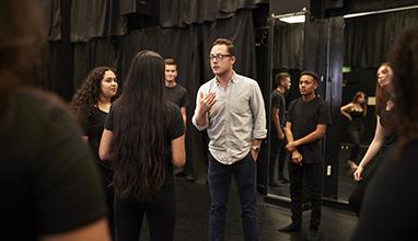 Man talking to a group of actors at a studio