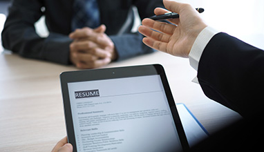Man looking at a resume on a tablet during an interview