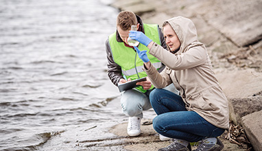 A man and woman toxicologist testing lake water with a testing tube