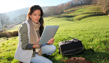 Woman wildlife biologist looking at her tablet in the middle of a field