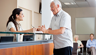 Woman medical receptionist talking with male patient in a medical office