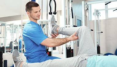 Males physical therapist stretching a patients leg