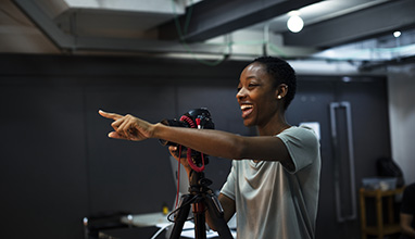 Photographer pointing at her subject while smiling at a studio