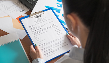 Businesswoman at a desk filled with documents looking at a resume