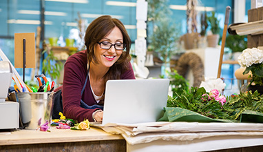 Woman store manager working on laptop in a flower shop