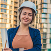 Portrait of an engineer woman wearing a hard hat standing in front of a building
