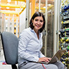 Woman technician using a laptop at a server room