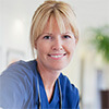 Woman wearing medical scrubs holding a paper cup