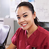 Woman wearing medical scrubs using a computer at a desk