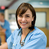 Woman wearing medical scrubs and a stethoscope around her neck revising medical forms