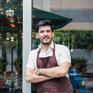 Male waiter standing in front of a restaurant