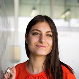 Portrait of a female teacher next to a blackboard with chalk in hand